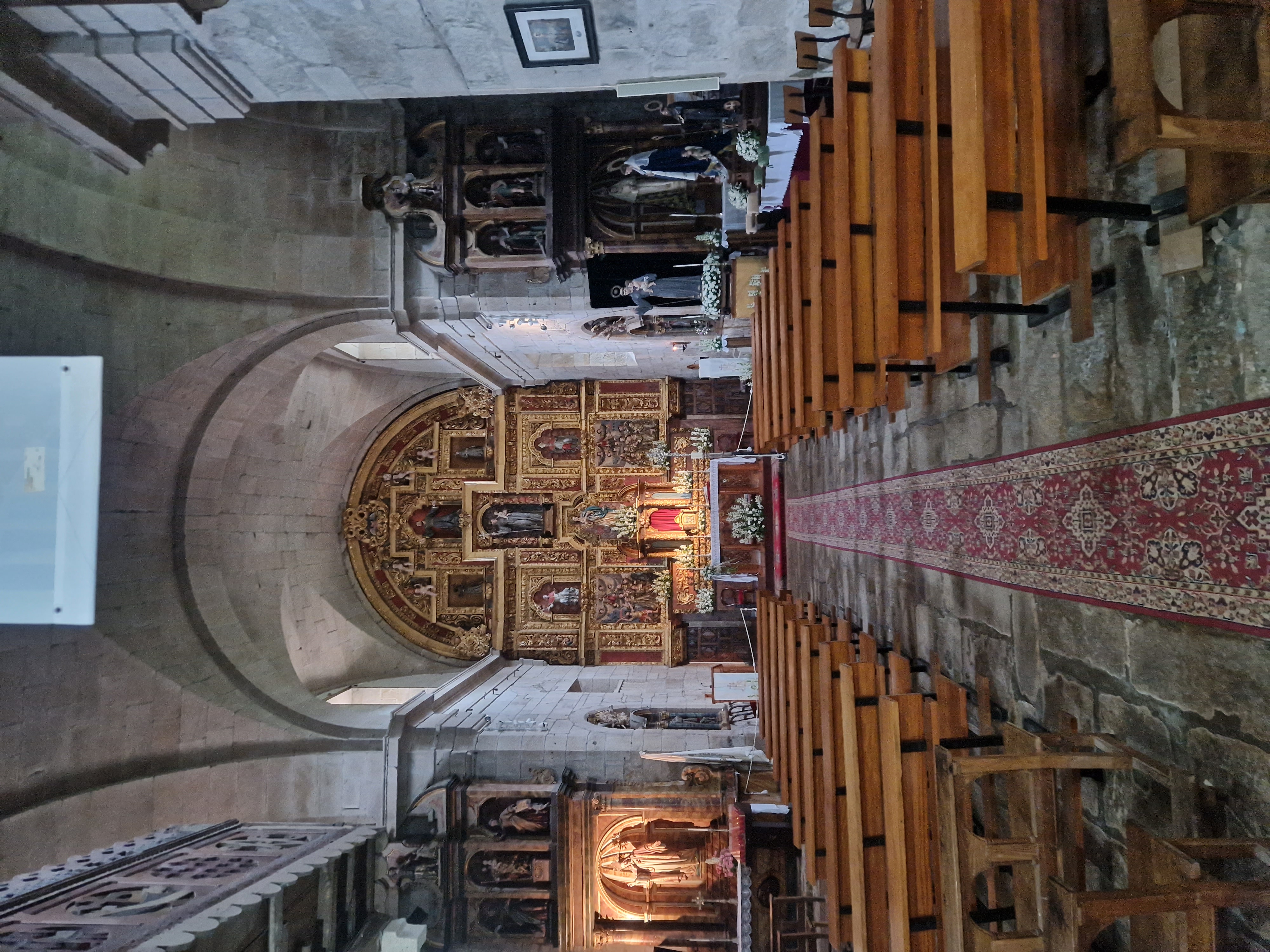 The inside of a church, with a decorated thin red carpet leading to a highly decorated golden altar